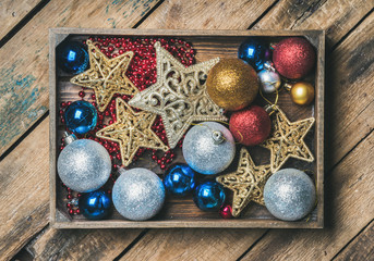 Christmas or New Year holiday decoration background. Christmas tree glittering toy stars, balls and garland in wooden box over rustic wooden background, top view, horizontal composition