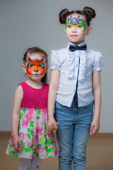 beautiful sisters with painted faces on a gray background. face painting