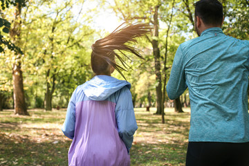 Young couple running together in park. Young people exercising. From back.