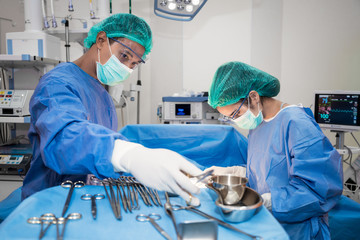 Asian doctor and an assistant in the operating room for surgical venous vascular surgery clinic in...