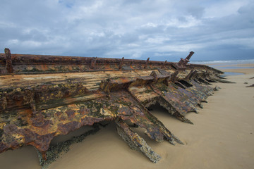 Shipwreck laying on a beach on fraser island Australia half covered in sand. vintage metal bits
