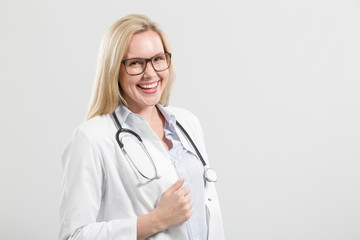 Fototapeta premium lächelnde junge hübsche Ärztin mit Stethoskop vor neutralem Hintergrund