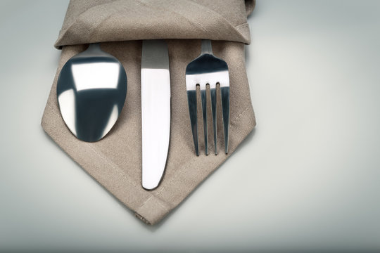 Cutlery in a napkin on a light background