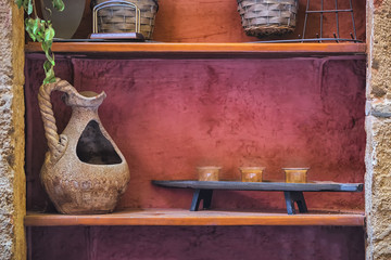 Picture of old handmade vintage vase with lanterns at the wooden shelf with red concrete wall at the background.