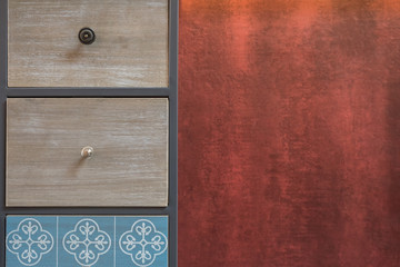 Picture of old handmade drawer organizer with red textured wall at the background.