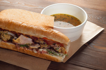 Street food, sandwich with chicken and bouillon on a wooden background
