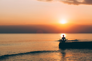 Young woman doing yoga by the sea