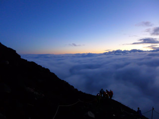 Naklejka na ściany i meble Blur image - People who are climbing on the top of Fuji mountain in Japan with blue sky and cloud at sunrise in the morning