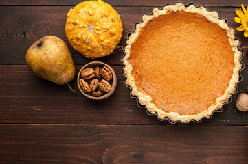 Obraz na płótnie Canvas pumpkin homemade pie at wooden background arranged with food ingredients top view