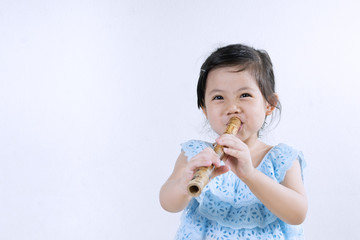 Thai Little Cute Girl in Traditional Dress Playing Thai Bamboo Flute. © poomsak