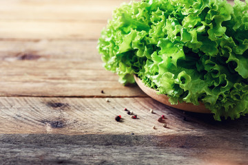 Obraz na płótnie Canvas Fresh organic lettuce salad on wooden background with pepper. Healthy food, raw and vegetarian concept with copy space.