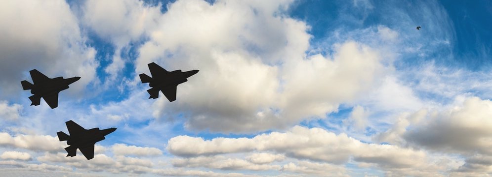 Fototapeta Silhouettes of three F-35 aircraft against the blue sky and white clouds