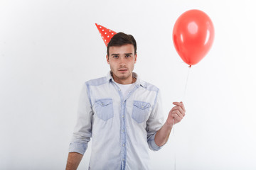 Picture of startled birthday guy holding red helium balloon and staring at camera with confused...