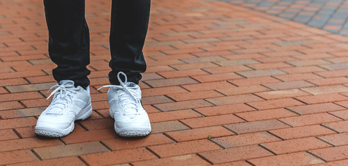lower part of the male legs in white sneakers