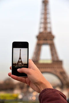 Woman taking photos with a smartphone to the Eiffel Tower
