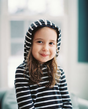 Portrait of a beautiful young girl sitting in a chair with a hoodie