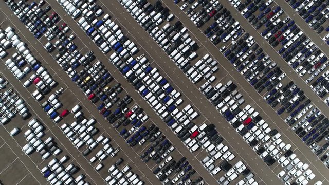 Aerial top down view of vehicle lot showing new produced cars by automakers stored there for further distribution towards car dealers port area where ships bring vehicles in mass production scene 4k