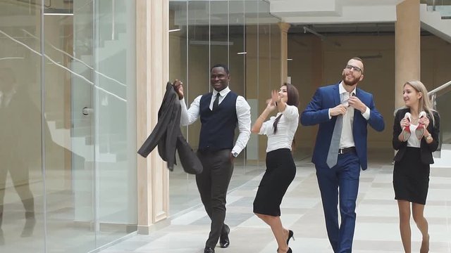 Slow motion. Group confident positive businesspeople exulting of winning. Business people walking along office corridor and celebrate the victory