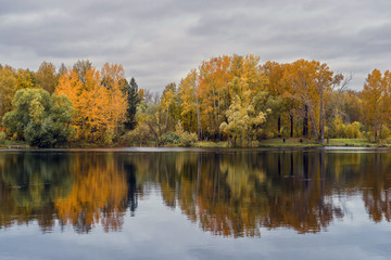 The lake, reflecting the cloudy sky and autumnal foliage trees