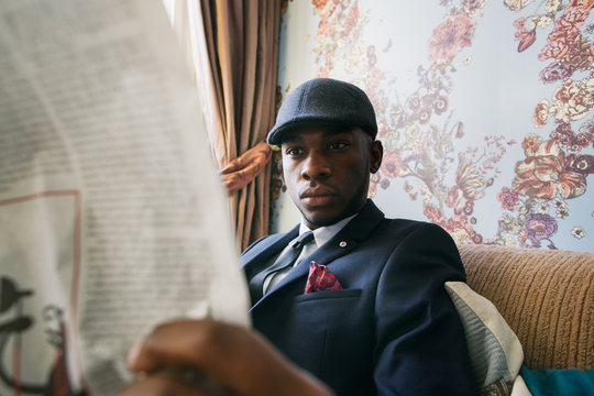 Close Up of Elegant Black Man Reading Newspaper in Colorful Living Room