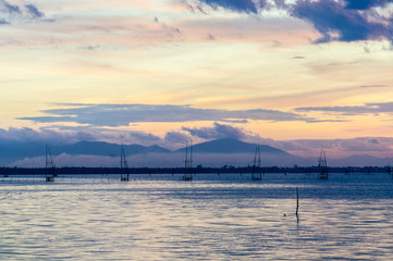 Twilight sky during sunset in Songkhla lake, southern Thailand with traditional fishing cage and mountain in background.