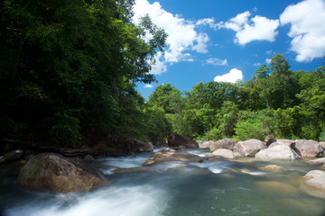 Waterfall in the south of Thailand with blue sky, clouds and lush vegetation in the background