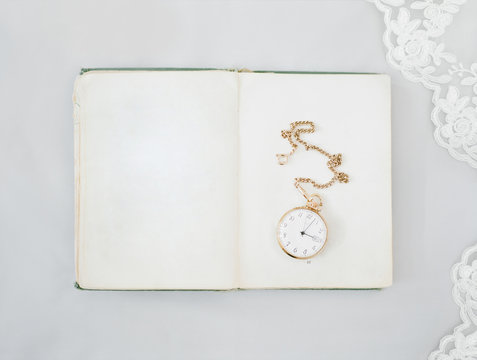 Golden watch on book against white background