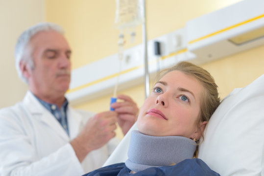 Doctor With Patient Wearing Neck Brace In Hospital Bed