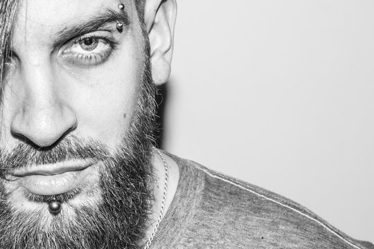 black and white portrait of a beautiful young man with a beard and piercing