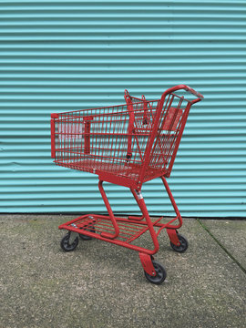 Red grocery cart in front of vibrant metal wall