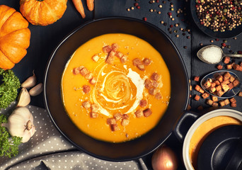 Fototapeta na wymiar Pumpkin creme soup served with croutons, crushed nuts and cream