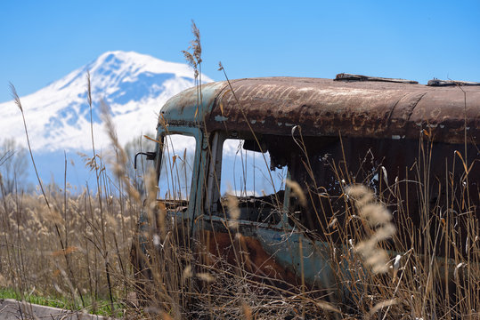 Abandoned and rusty old Soviet Russian bus in the middle of reeds and with scenic Ararat mountain on the background in rural Southern Armenia in Ararat province on 4 April 2017.
