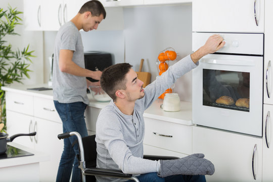 disabled man and his friend preparing meal in the kitchen