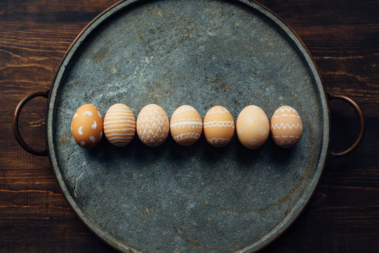 Seven decorated eggs aligned on a stone plate