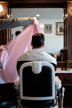 A Gentleman Barber Draping A Barber Cape Over A Client.