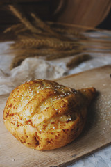 Fresh bread and wheat ears on rustic wooden board