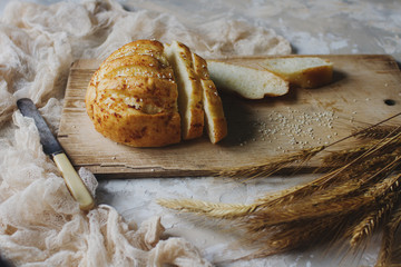 Fresh bread and wheat ears on rustic wooden board
