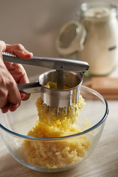 Close-up of man ricing peeled potatoes