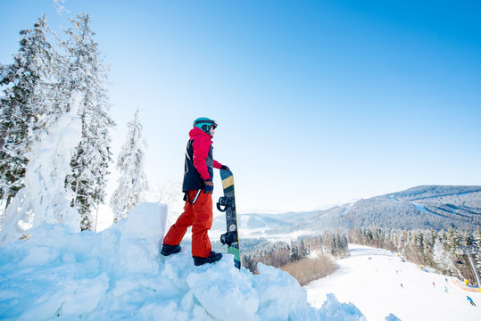 Full length shot of a male snowboarder standing on top of a slope looking around enjoying the view on sunny winter day at ski resort Bukovel, Ukraine copyspace mountains landscape lifestyle concept