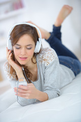 Naklejka premium a beautiful young woman listening to music in bed