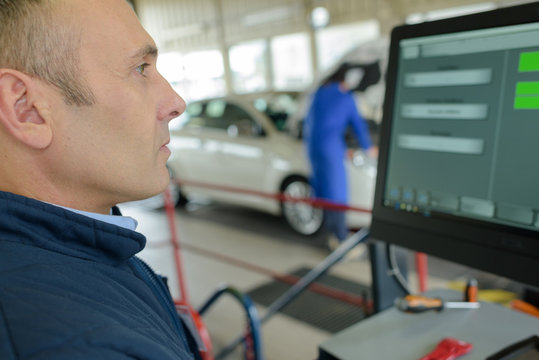 image of male mechanic is checking tires on computer
