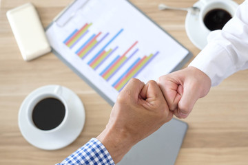 Asian business people joining hands with colleagues together at meeting time for develop job to success during discussing document about finance on table at meeting time., business colleagues teamwork