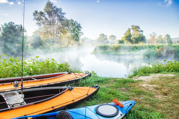 Three kayaks anchored at bank in camping on river shore glade at beautiful outdoor nature background. Seversky Donets river, Ukraine. © Feel good studio