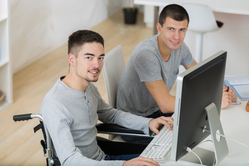 student in wheelchair typing on his laptop in classroom