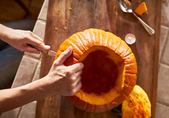 Obraz premium top down view of a woman carving a pumpkin in ktichen