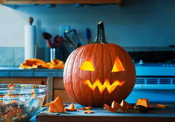 creepy halloween jack o lantern pumpkin in kitchen glowing right after it was carved