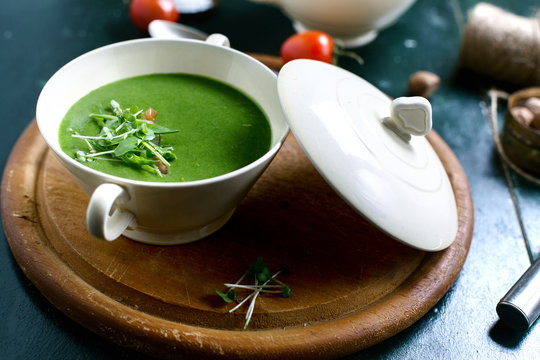 A bowl of spinach soup on a wooden board.