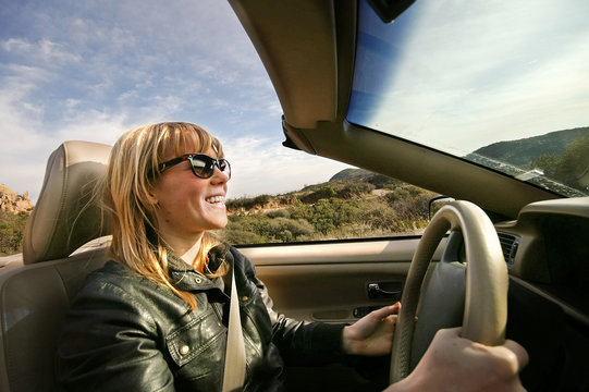 Excited young woman driving a convertible