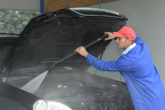 image of worker cleaning the cars engine with a karcher