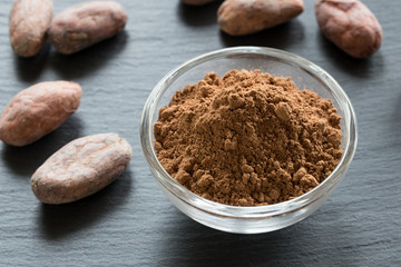 Raw cocoa powder, with cacao nibs in the background